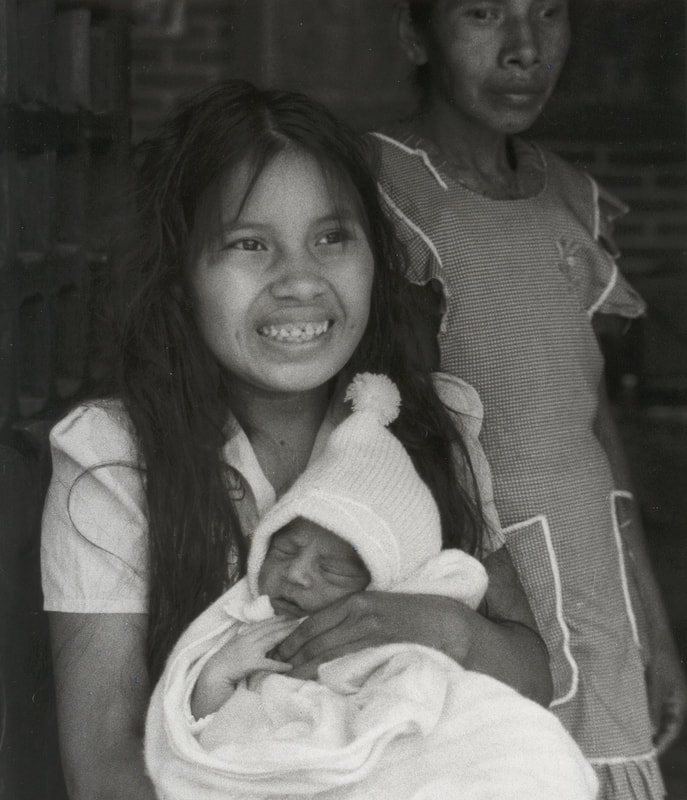 Natividad a la edad de 15 años abrazando a su bebé recién nacido con su madre en el fondo, días después de que se convirtiera en madre. En Rancho Viejo, Xalapa, Veracruz. Mexico