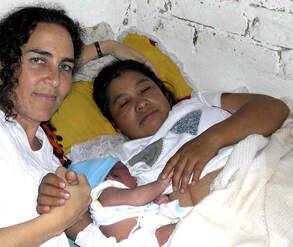 La partera Naoli Vinaver agarrada de la mano con la madre y el bebé recién nacido, momentos después del parto en el hogar de la parturienta, en Rancho Viejo, Xalapa, Veracruz. Mexico