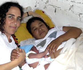Midwife Naoli Vinaver holding hands with the mother and newborn baby, moments after the home birth happened at the parturient's house, in Rancho Viejo, Xalapa, Veracruz. Mexico